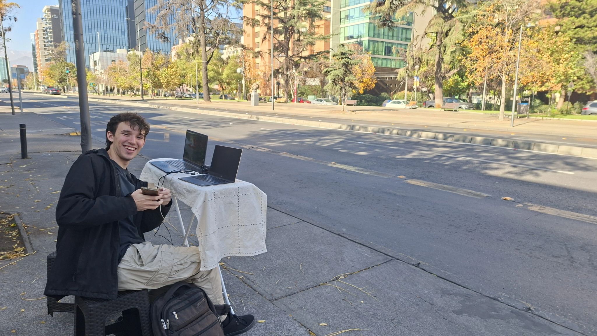 Nicolás Quintana working on debri net outdoors with two laptops on a sidewalk